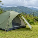 Green camping tent with an open entrance overlooking lush tropical hills