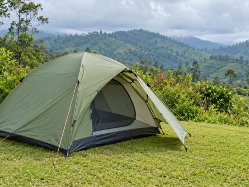 Green camping tent with an open entrance overlooking lush tropical hills